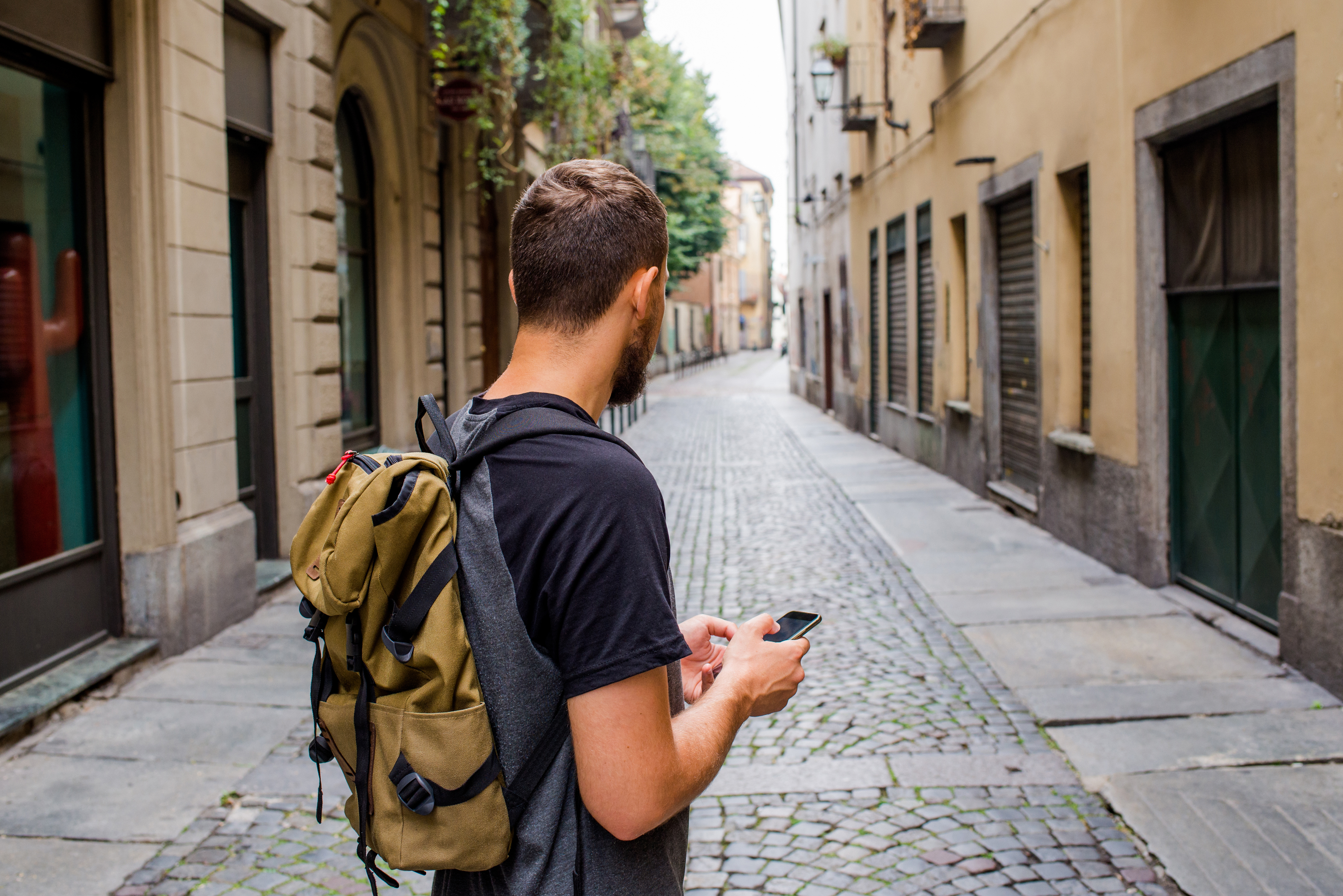 A man holding a phone in a thin street in Europe