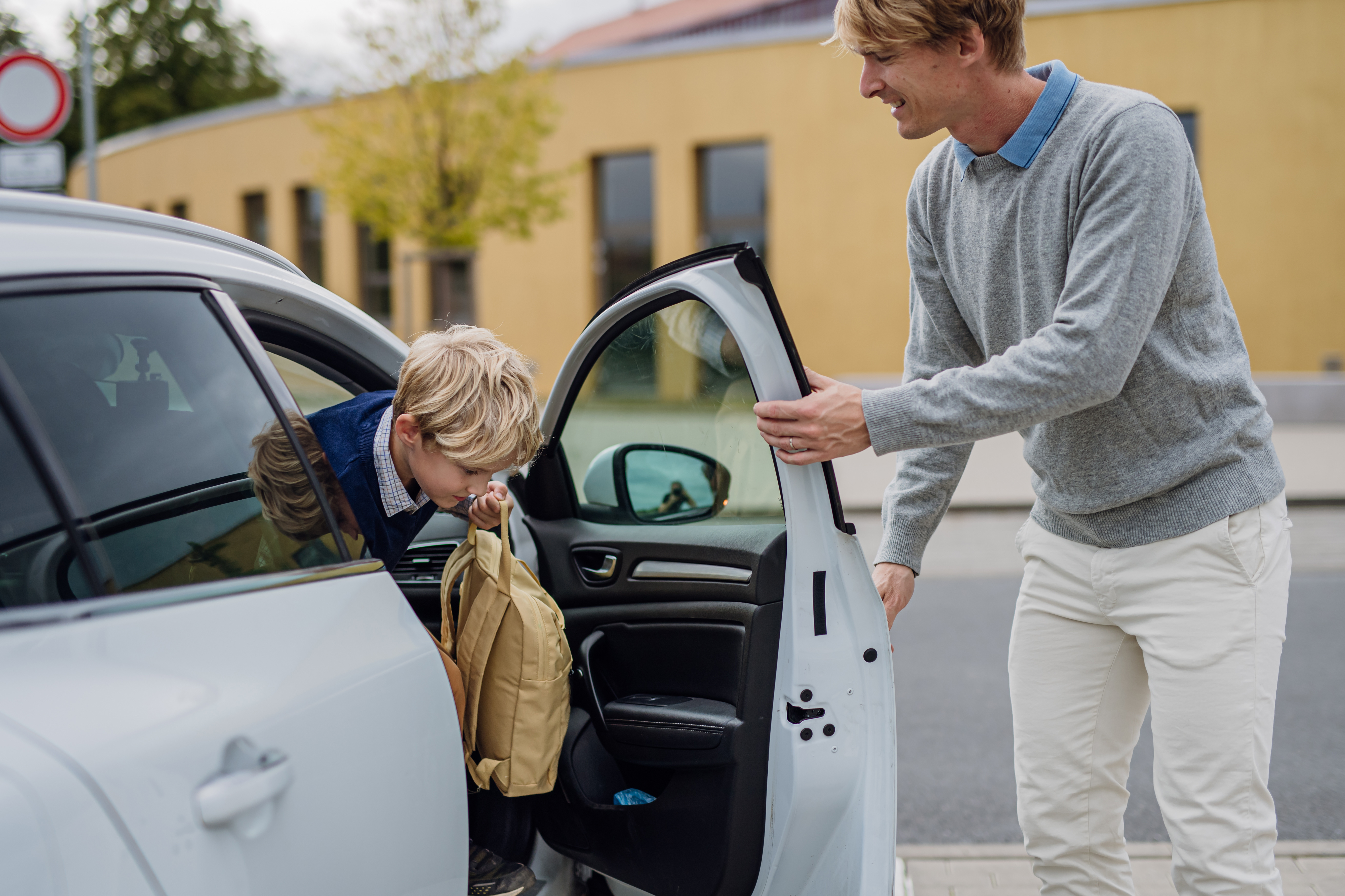 Kid with a backpack leaving his dad's car to go to school