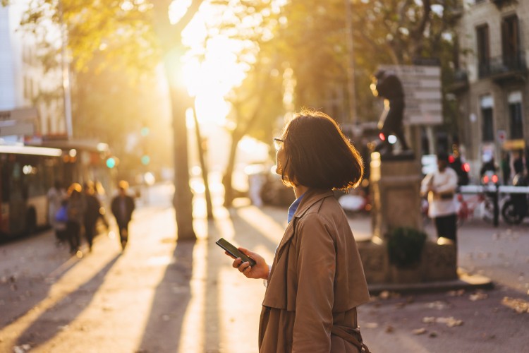 Girl looking around in a city with a smartphone in her hand. 