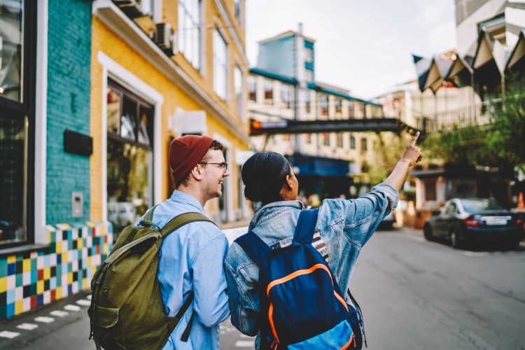Back view of male and female backpackers enjoying a city