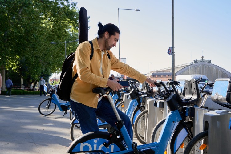 A man standing next to a bike sharing dock. 