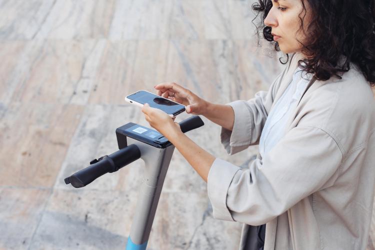 Woman scanning a code with her smartphone on an electric scooter
