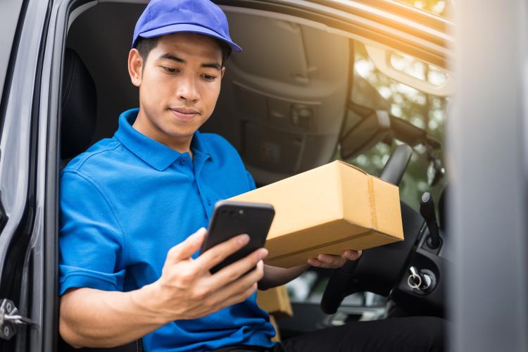 A courier with a parcel and a phone. 