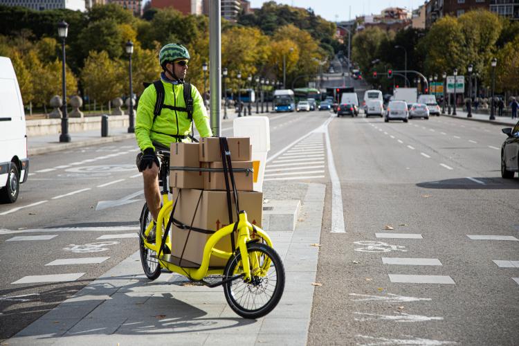 A man riding a cargo bike loaded with parcels. 