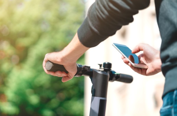 Man using a phone next to his scooter