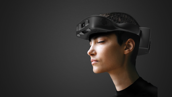 Side profile of a person with closed eyes wearing the .lumen Glasses for the Blind, an AI-powered wearable mobility device. The matte black headset wraps around the head and features front-facing cameras and sensors for real-time navigation. The subject is shown against a dark background with ample negative space, highlighting the ergonomic design of the device.