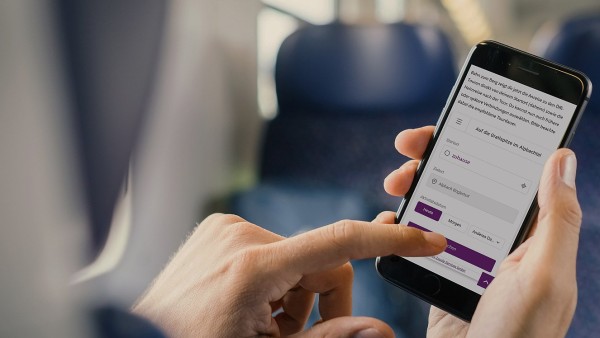 Mobile phone held with right hand and left hand about to query the timetable