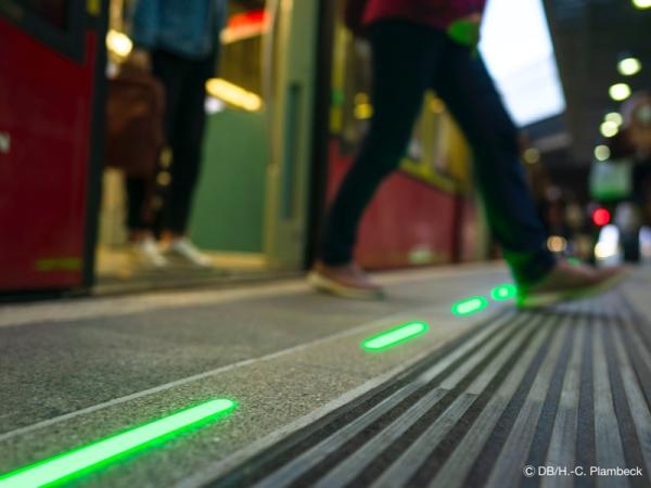 Passengers boarding and alighting from a train at a station with the Illuminated Platform Edge by SIUT, showing integrated green lighting for safety and orientation.
