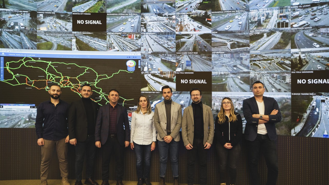 Group photo of team standing in front of monitor