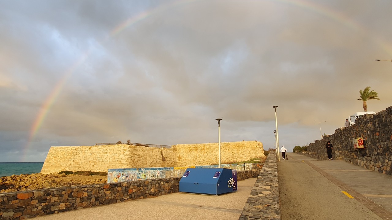 A smart and secure bike on the seaside in Heraklion, Crete, Greece, under a rainbow on an autumn day