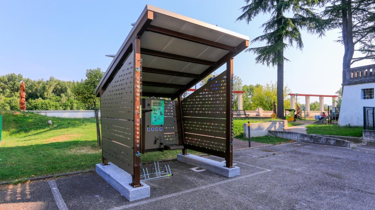 Front view of a compact solar charging shelter with visible electrical outlets and a modern design.