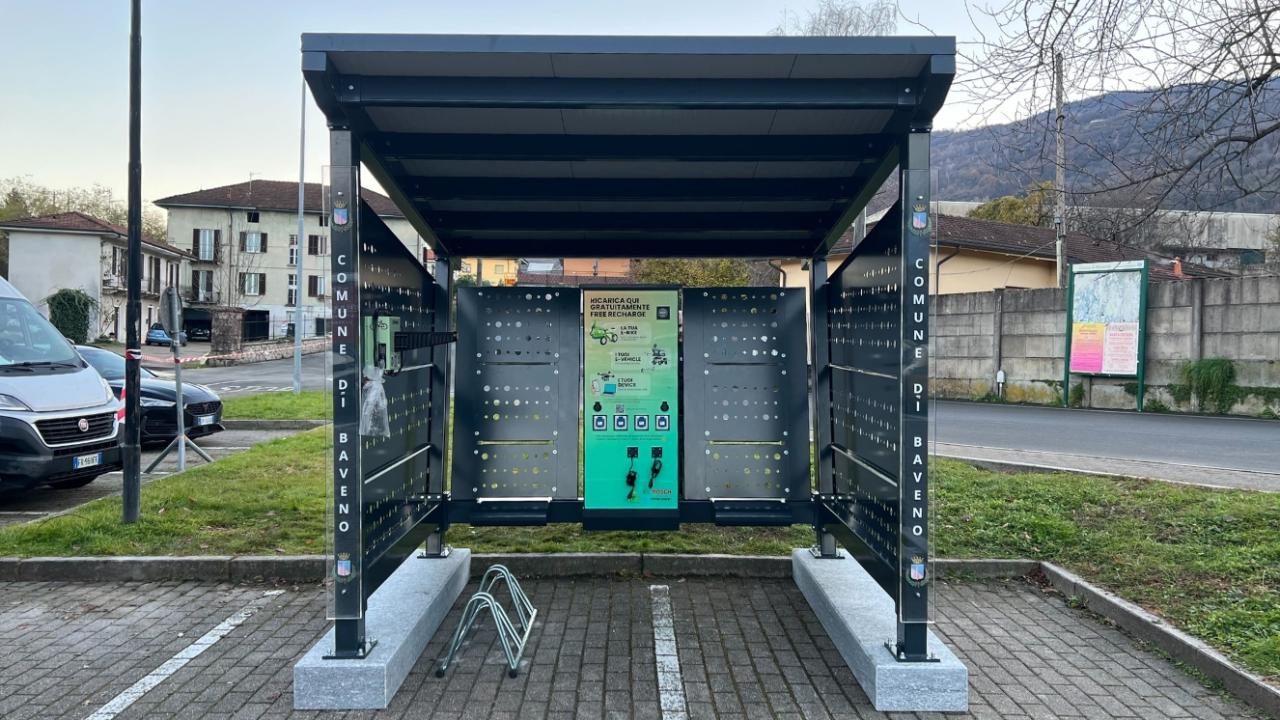 A modern solar-powered shelter with the "Comune di Baveno" branding and bike racks.