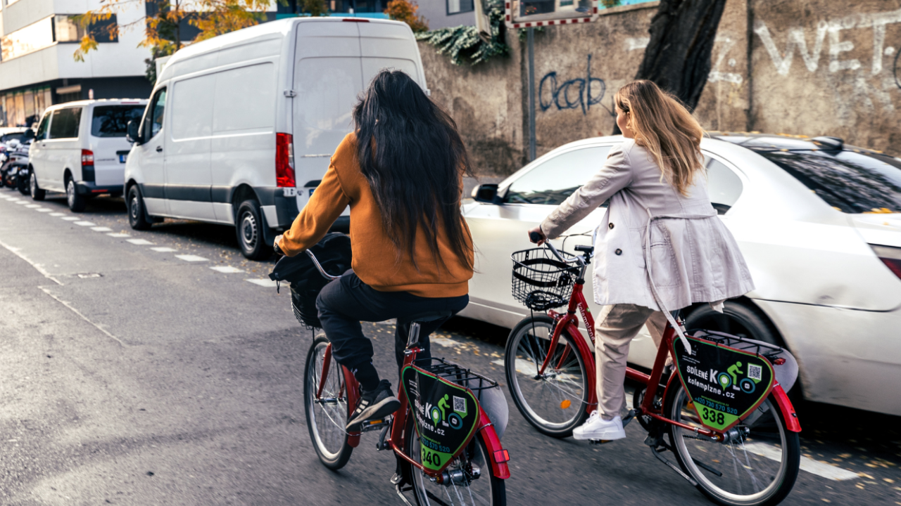 Man with long hair and woman with long hair riding two shared bicycles